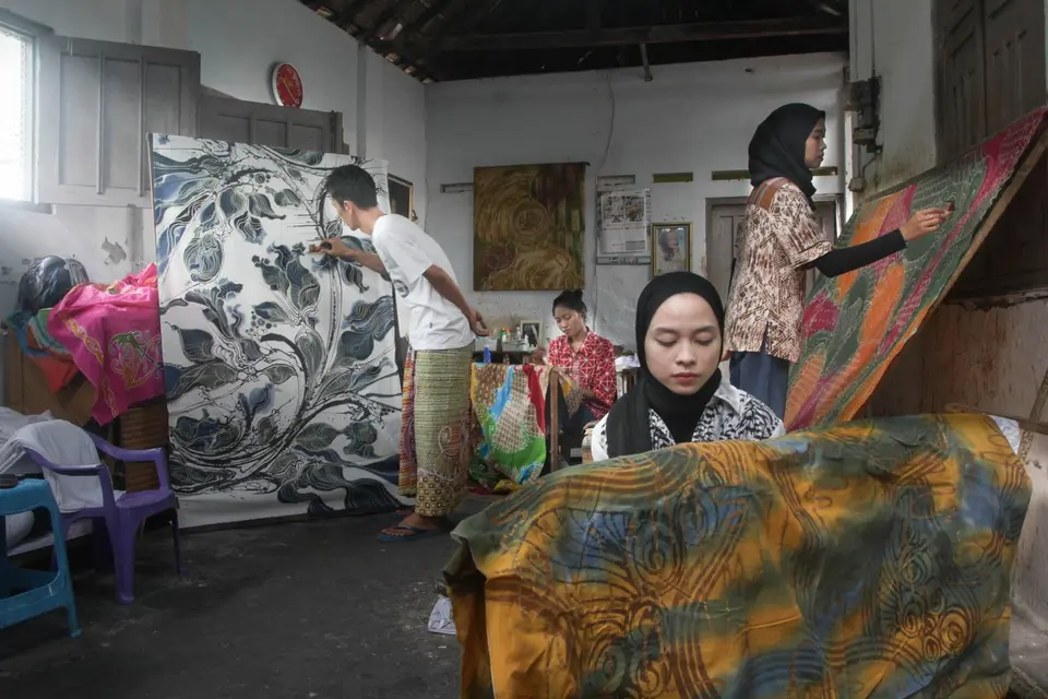 Perajin membatik kain dengan canting di sebuah rumah batik Laweyan