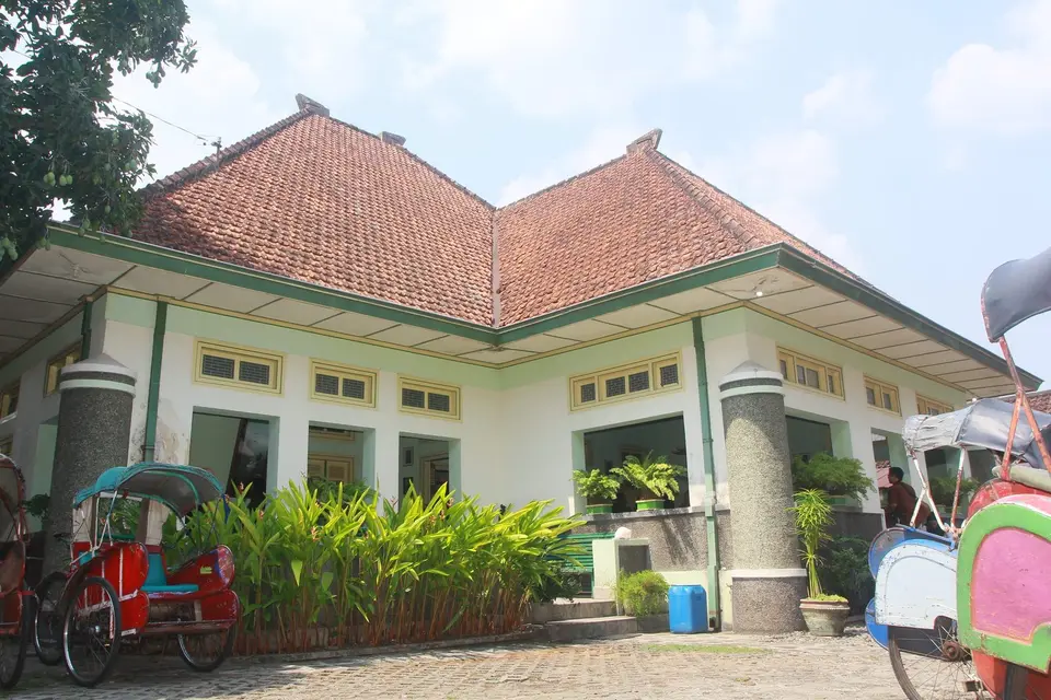 Rumah kuno beratap merah dengan becak di depannya di Laweyan